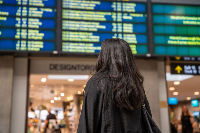 Resenär tar del av trafikinformation på en station.