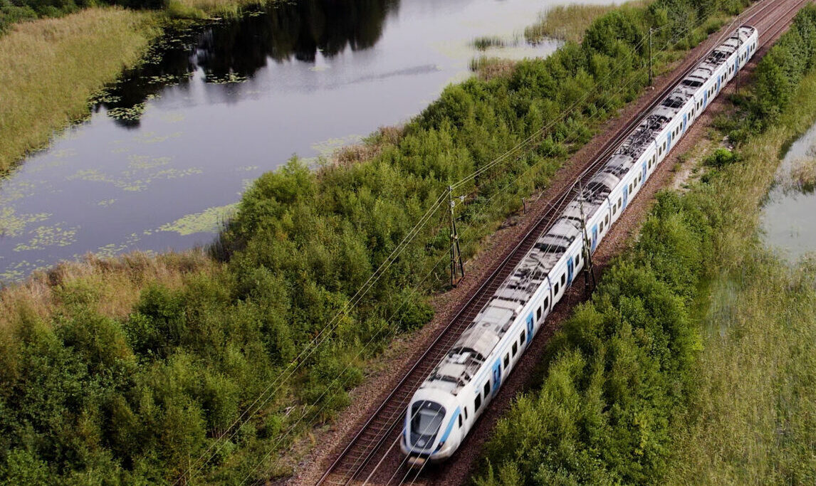 Tåg trafikerar järnvägen genom ett svenskt landskap.
